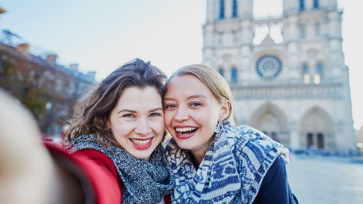 Friends taking a selfie in front of Notre-Dame Cathedral