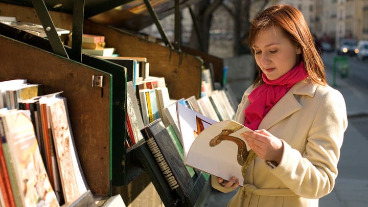 Woman browsing outdoor bouquinistes book stalls in Paris